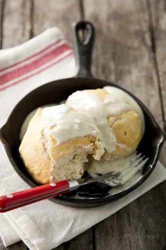 Paula Deen biscuits with milk gravy served split open in a cast iron skillet