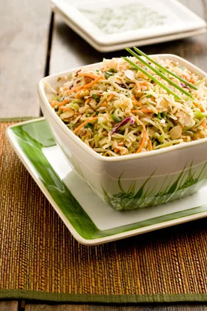 A bowl of broccoli cole slaw with toasted ramen noodles, almonds, and sunflower seeds