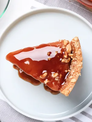 Paula Deen Caramel Apple Cheesecake with warm caramel topping and pecans on a graham cracker crust