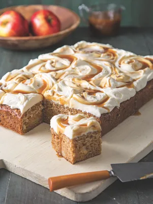 A slice of Paula Deen caramel apple spice cake topped with cream cheese frosting and a caramel drizzle