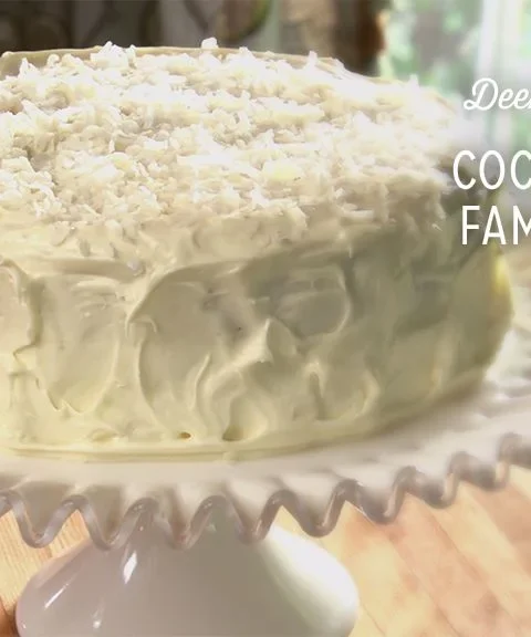 Paula Deen Coconut Cake with cream cheese frosting and coconut flakes on a serving plate