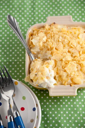 Creamy hash brown casserole topped with crushed potato chips in a baking dish