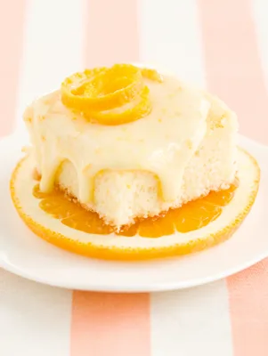 Orange brownies topped with cream cheese frosting cut into squares on a plate