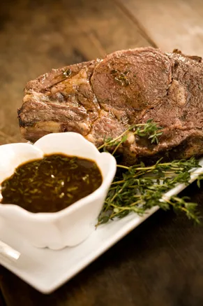 Roast prime rib of beef on a platter with a rich pan sauce
