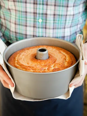 Paula Deen almond sour cream pound cake baked in a tube pan and held on a kitchen towel