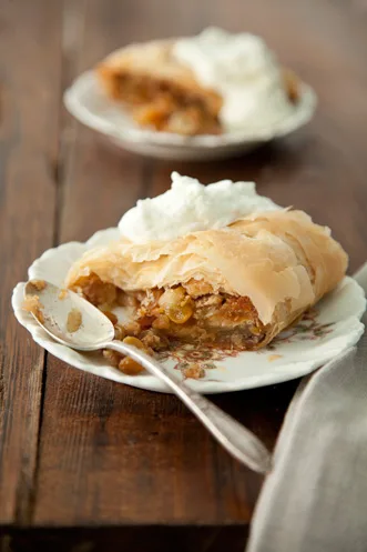 Paula Deen apple strudel slice with flaky phyllo, apple raisin filling and whipped cream on a vintage plate