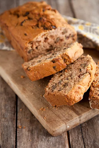 Paula Deen applesauce bread sliced on a wooden cutting board showing raisins and walnuts in the crumb