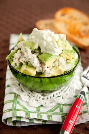 Paula Deen avocado chicken salad in a green glass bowl topped with avocado dressing next to toasted crusty bread