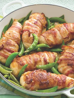 Paula Deen bacon-wrapped chicken with sugar snap peas in a white skillet with crispy browned bacon