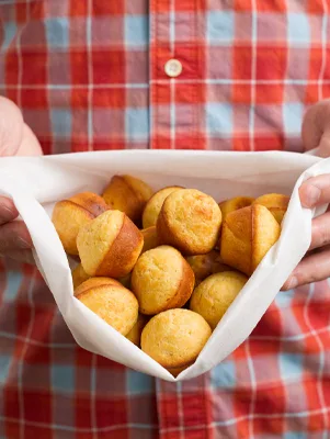 Paula Deen baked hush puppies, golden cornmeal muffin bites, held in a white napkin