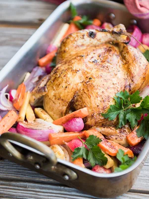 Paula Deen baked sticky honey chicken roasted golden in a roasting pan with carrots, parsnips, radishes and red onion