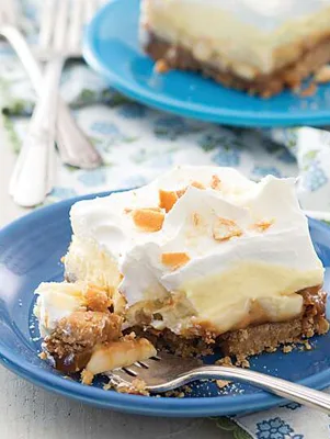 Paula Deen banana pudding caramel bars with vanilla wafer crust, caramel, banana, pudding and whipped cream on a blue plate