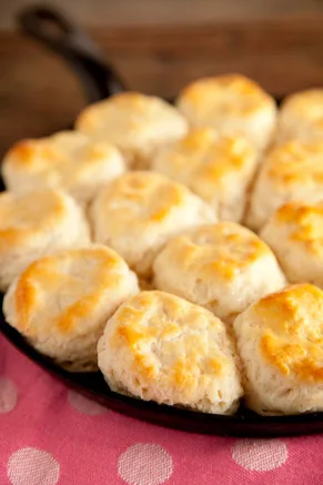 Paula Deen biscuits baked golden brown in a black cast iron skillet on a pink polka dot cloth