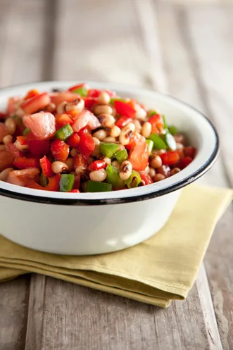 Paula Deen black-eyed pea salad with diced red and green bell peppers and tomato in a white enamel bowl
