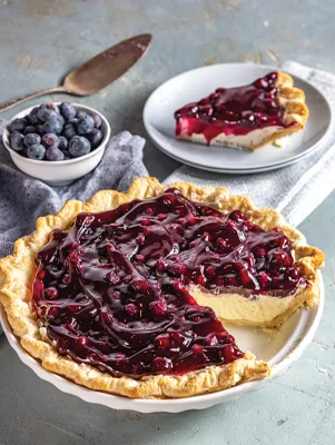 Paula Deen blueberry cream pie with a golden crust and glossy blueberry topping, one slice cut out and served on a plate