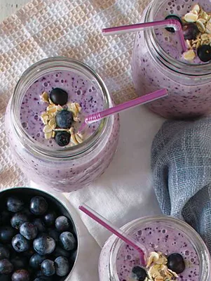 Paula Deen blueberry muffin smoothie in mason jars with pink straws, topped with fresh blueberries and rolled oats