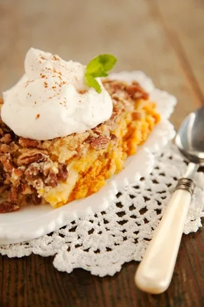 Paula Deen Bobby's lighter pumpkin crunch slice topped with whipped cream, cinnamon and a mint leaf on a white plate