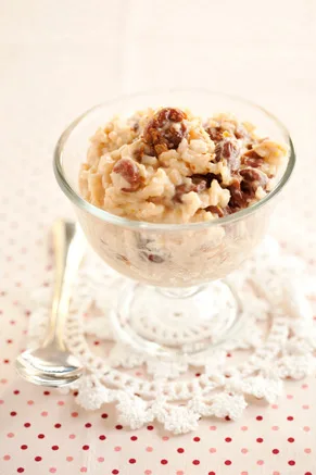 Paula Deen Bobby's rice pudding with dried cherries in a glass dessert dish with a spoon beside it