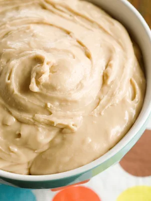 Bowl of creamy Paula Deen brown butter icing swirled smooth with a light caramel color