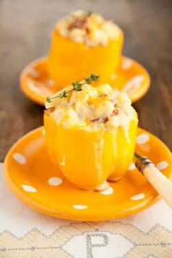 Paula Deen brunch stuffed peppers: yellow bell peppers filled with cheesy egg and bacon, topped with a thyme sprig, on orange polka dot plates