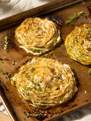 Paula Deen cabbage steaks roasted golden brown with fresh thyme on a baking sheet