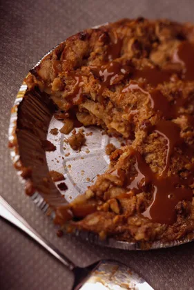 Paula Deen Caramel Apple-Nut Crumb Pie with golden walnut crumb topping and caramel drizzle, partly sliced in a pie plate