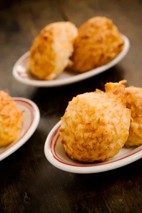 Paula Deen cheese biscuits, golden and craggy, served on small red-rimmed oval dishes on a dark wooden table