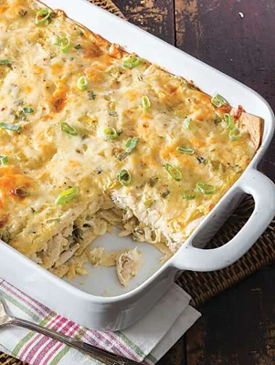 Paula Deen chicken enchilada casserole in a white baking dish topped with melted cheese and chopped green onion