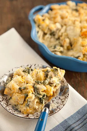 Paula Deen chicken florentine casserole with spinach and a golden breadcrumb topping, served on a patterned plate beside a blue baking dish