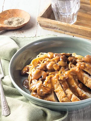 Paula Deen chicken Marsala sliced and topped with mushroom Marsala sauce over spaghetti in a gray-green bowl