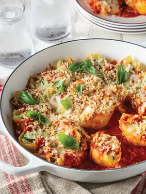Paula Deen chicken parmesan stuffed shells in a white baking dish topped with melted mozzarella, golden panko and fresh basil leaves