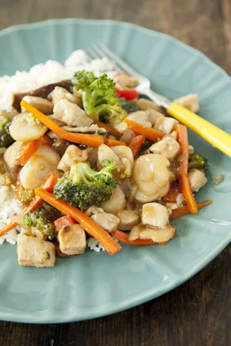 Paula Deen chicken stir fry with broccoli, carrots, water chestnuts and shiitake mushrooms over white rice on a blue plate