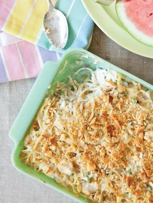 Paula Deen chicken tetrazzini in a mint green baking dish with a golden panko topping, peas and noodles visible