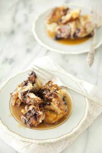 Paula Deen chocolate bread pudding with rum toffee sauce served on two white plates with forks