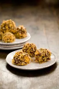 Paula Deen chocolate peanut butter balls coated in crushed corn cereal on white plates on a wooden table