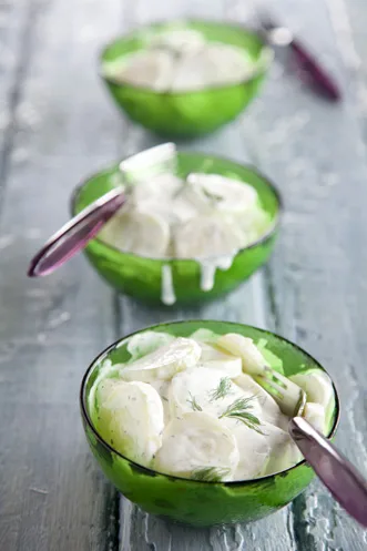 Paula Deen cold cucumber salad with creamy dill dressing served in three green glass bowls with fresh dill