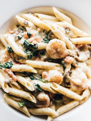 Paula Deen company shrimp and mushroom pasta with penne, shrimp, spinach and mushrooms in a creamy sauce in a white bowl