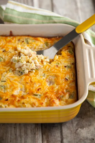 Paula Deen corn spoon bread baked in a yellow dish with a golden cheddar top and a spoonful lifted out