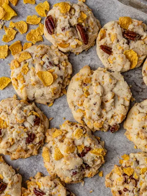 Paula Deen cornflake cookies with pecans and golden cornflakes baked on a parchment lined baking sheet