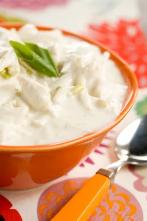 Paula Deen crab soup, a creamy white crab soup in an orange bowl topped with fresh green onion