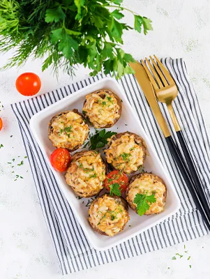 Paula Deen crab-stuffed mushrooms baked golden in a white dish with parsley and cherry tomatoes