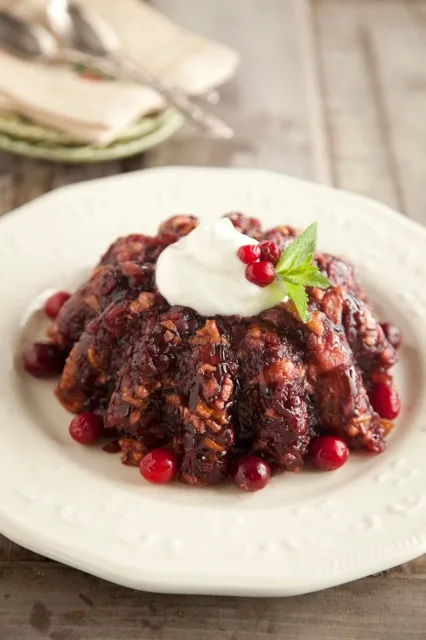 Paula Deen cranberry salad unmolded on a white plate topped with whipped cream, a mint sprig and fresh cranberries