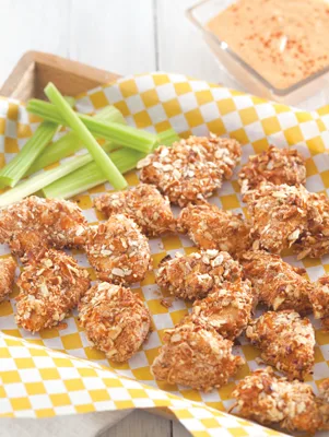 Paula Deen crispy chicken bites with spicy ranch dip served in a basket with celery sticks on yellow checkered paper