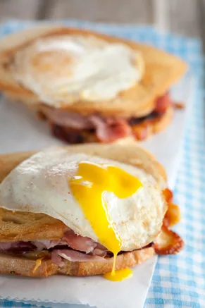 Paula Deen croque madame sandwich topped with a fried egg with runny yolk over ham and golden sourdough on parchment paper