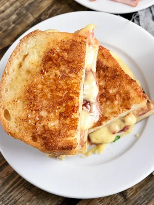Paula Deen Cuban sandwich cut in half on a white plate with crispy golden sourdough, melted American cheese and ham