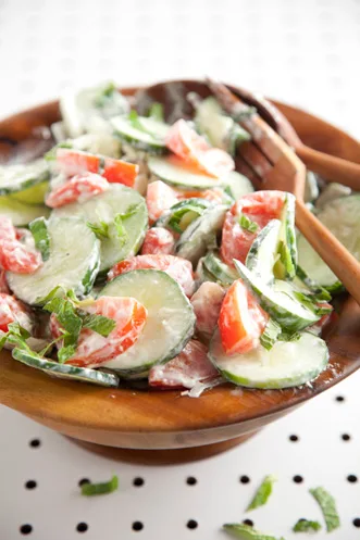 Paula Deen cucumber, tomato, mint salad with sliced cucumbers, tomato pieces and shredded fresh mint in a wooden bowl
