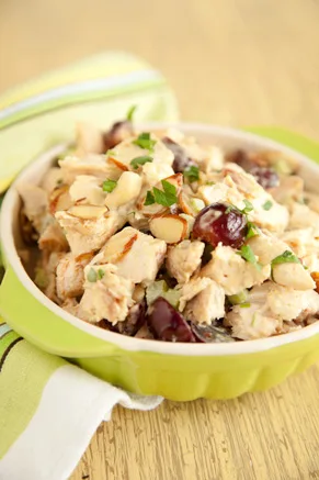 Paula Deen curry chicken salad with cubed chicken, red grapes, slivered almonds and parsley in a green bowl