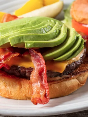 Paula Deen Deen Burger topped with avocado slices, crispy bacon and melted Cheddar on a toasted bun