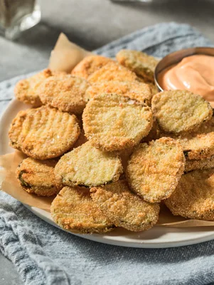 Paula Deen deep-fried pickles, golden cornmeal-crusted pickle slices piled on a plate with a small dish of honey mustard sauce