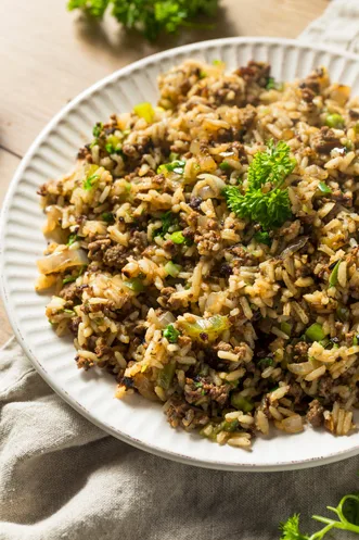 Paula Deen dirty rice with sausage, chicken livers, celery and fresh parsley served on a white plate